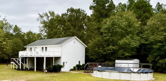 rear view of property with a yard, a swimming pool side deck, and a shed