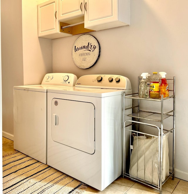 clothes washing area featuring washer and dryer, light tile patterned flooring, and cabinets