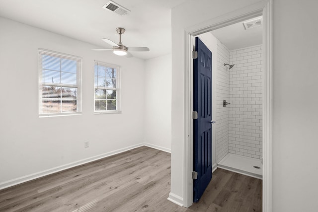 bathroom with hardwood / wood-style flooring, ceiling fan, and tiled shower