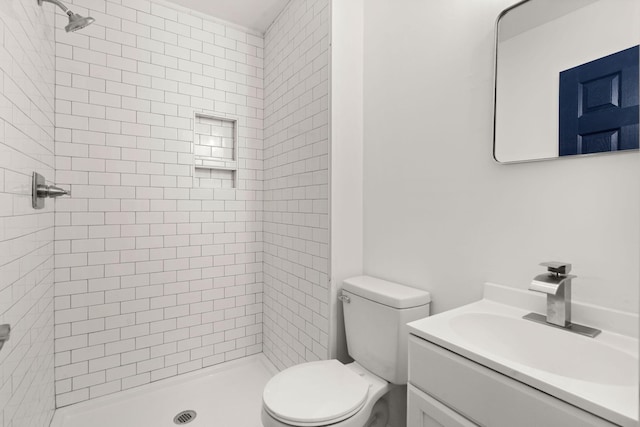 bathroom featuring a tile shower, vanity, and toilet