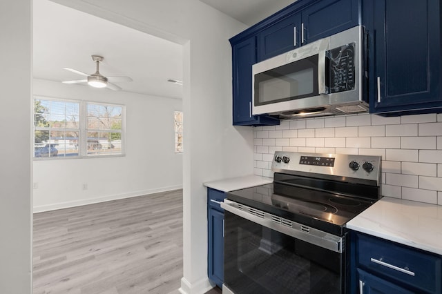 kitchen with light wood-type flooring, blue cabinets, stainless steel appliances, and tasteful backsplash