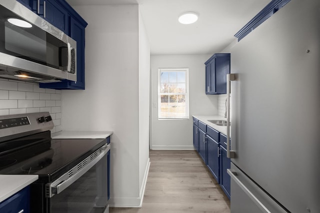 kitchen featuring light hardwood / wood-style flooring, stainless steel appliances, and blue cabinets