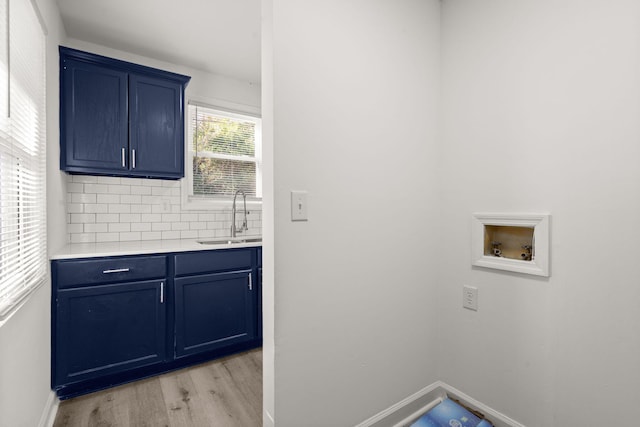 clothes washing area with cabinets, sink, hookup for a washing machine, and light hardwood / wood-style flooring