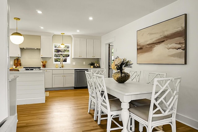 2456 Lantern St, Charleston, SC 29414 - kitchen with stainless steel dishwasher, light wood-style flooring, hanging light fixtures, white cabinets, and recessed lighting
