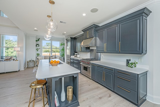 kitchen featuring a center island with sink, stainless steel stove, light countertops, a sink, and under cabinet range hood