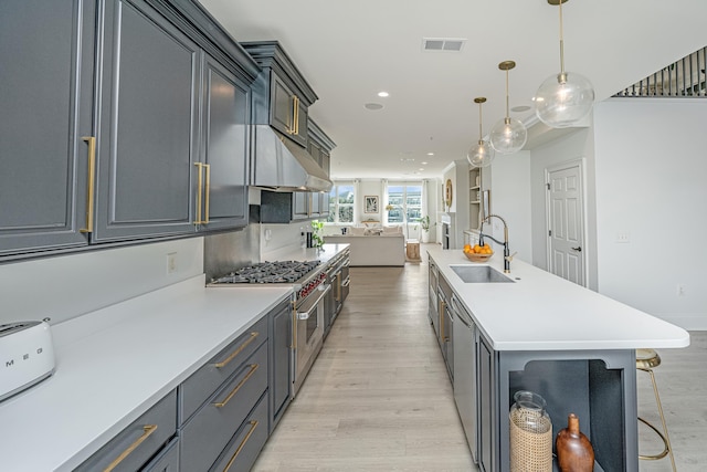 kitchen with visible vents, open floor plan, light countertops, pendant lighting, and a sink