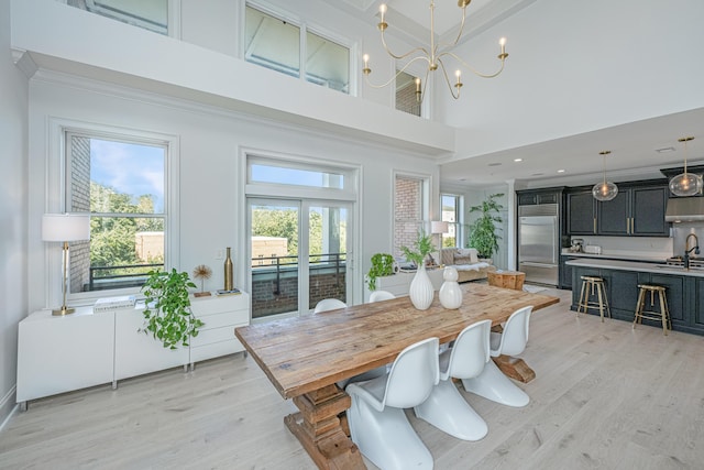 dining area with ornamental molding, plenty of natural light, light wood-style flooring, and an inviting chandelier