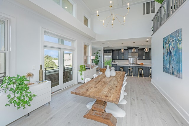 dining room with light wood finished floors, baseboards, visible vents, and a chandelier