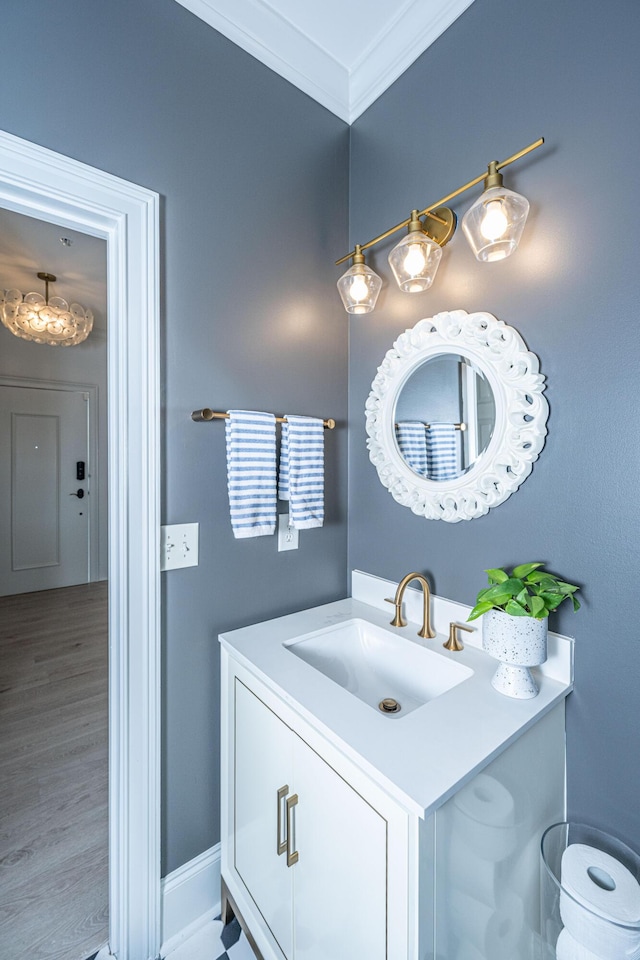 bathroom featuring ornamental molding, wood finished floors, vanity, and baseboards