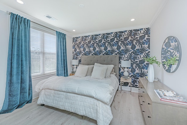 bedroom featuring crown molding, visible vents, an accent wall, light wood-type flooring, and wallpapered walls