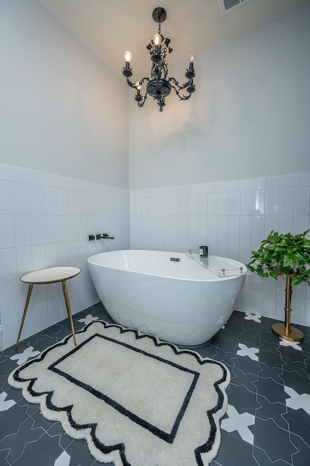 bathroom with a chandelier, wainscoting, a freestanding tub, and tile walls