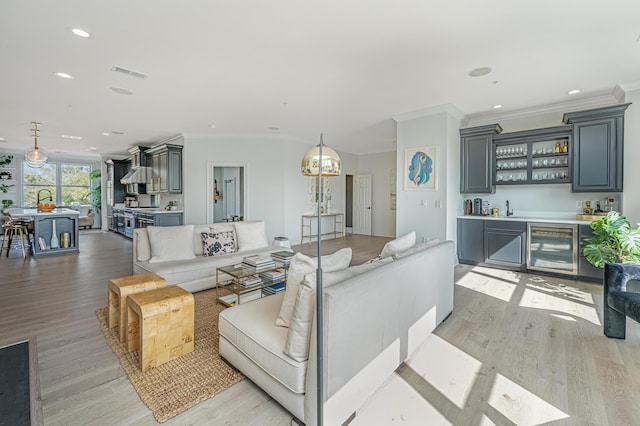 living room featuring wine cooler, indoor wet bar, light wood finished floors, recessed lighting, and visible vents