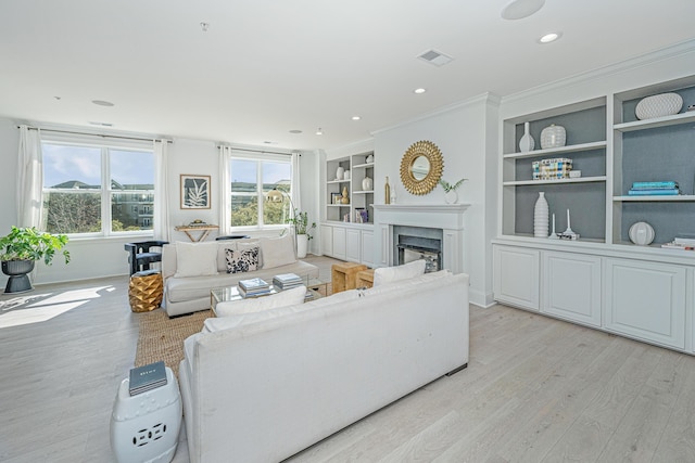 living area with light wood finished floors, a fireplace, visible vents, and built in features