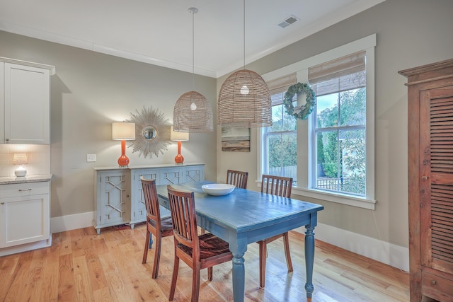 dining room with crown molding and light hardwood / wood-style flooring