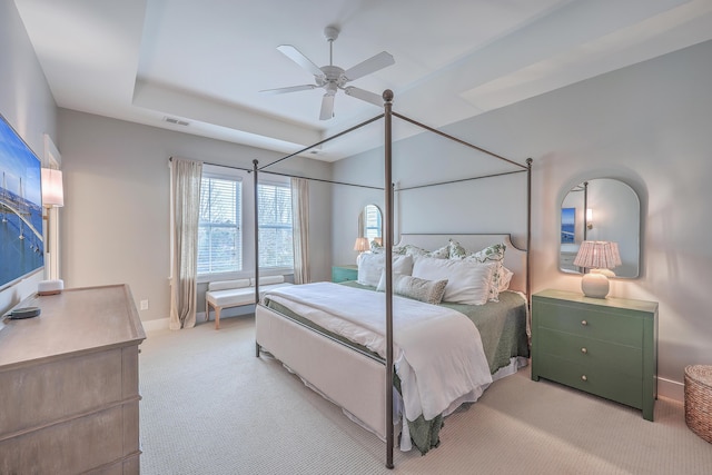 carpeted bedroom featuring ceiling fan and a tray ceiling