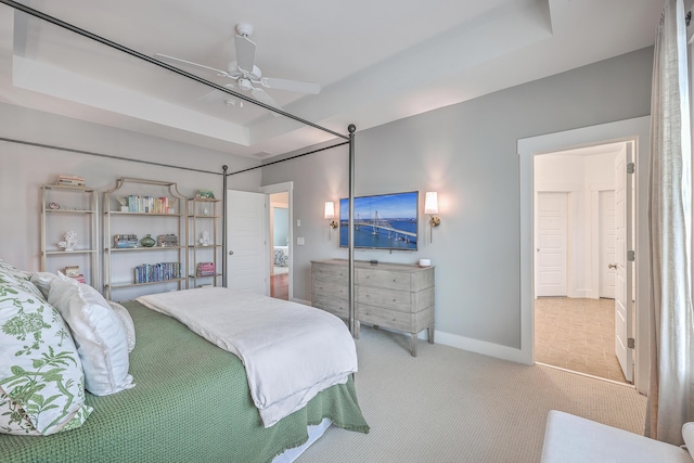 carpeted bedroom featuring ceiling fan and a tray ceiling