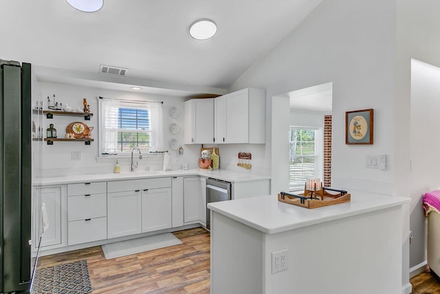 kitchen featuring stainless steel appliances, vaulted ceiling, visible vents, a healthy amount of sunlight, and a sink