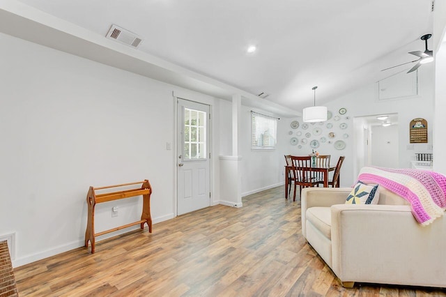 sitting room with baseboards, vaulted ceiling, visible vents, and light wood-style flooring