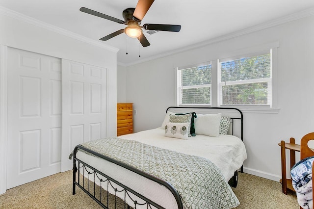 carpeted bedroom with ceiling fan, baseboards, crown molding, and a closet