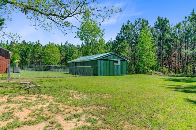 view of yard with fence, an outbuilding, a pole building, and a wooded view