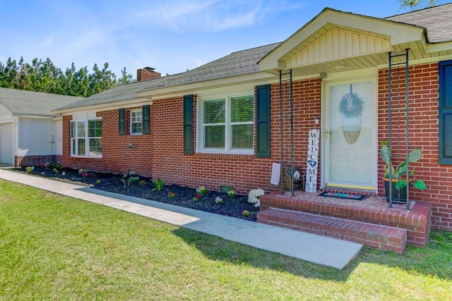 single story home with brick siding, a chimney, and a front yard