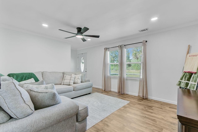 living area featuring light wood finished floors, a ceiling fan, visible vents, and ornamental molding
