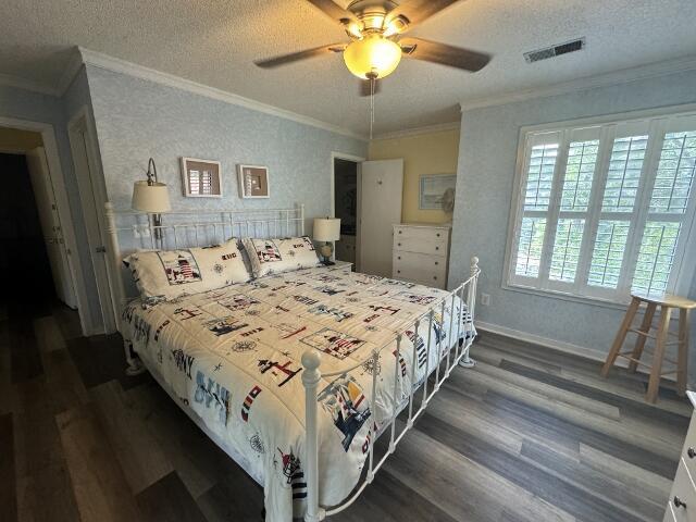 bedroom featuring crown molding, visible vents, dark wood finished floors, and a textured ceiling