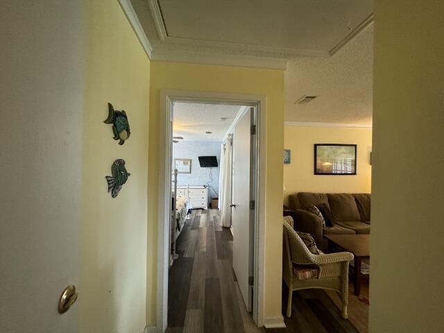 hall featuring attic access, dark wood-style flooring, visible vents, and crown molding