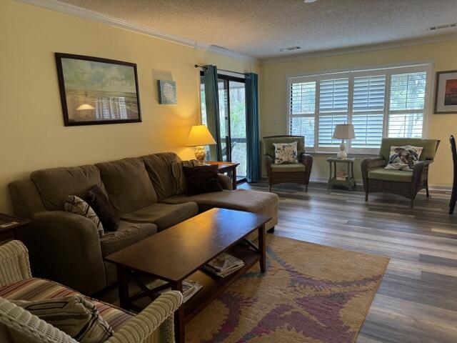 living area featuring dark wood-style flooring, crown molding, and a textured ceiling