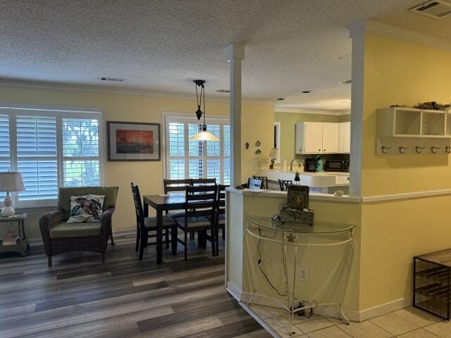 kitchen featuring visible vents, white cabinets, light countertops, crown molding, and pendant lighting