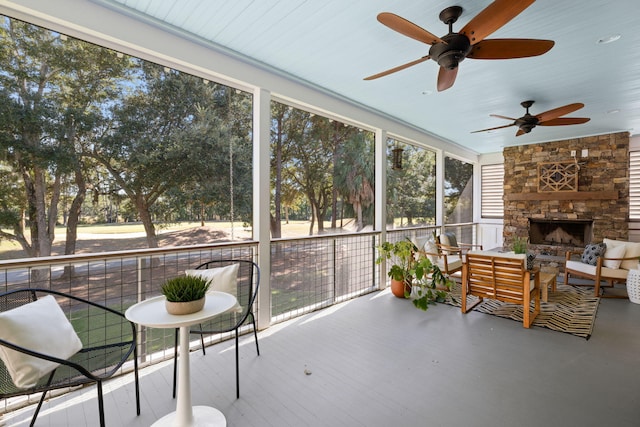 sunroom / solarium featuring ceiling fan and a fireplace