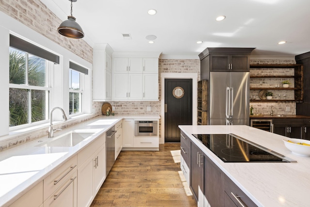 kitchen featuring white cabinetry, stainless steel appliances, dark brown cabinets, decorative light fixtures, and sink