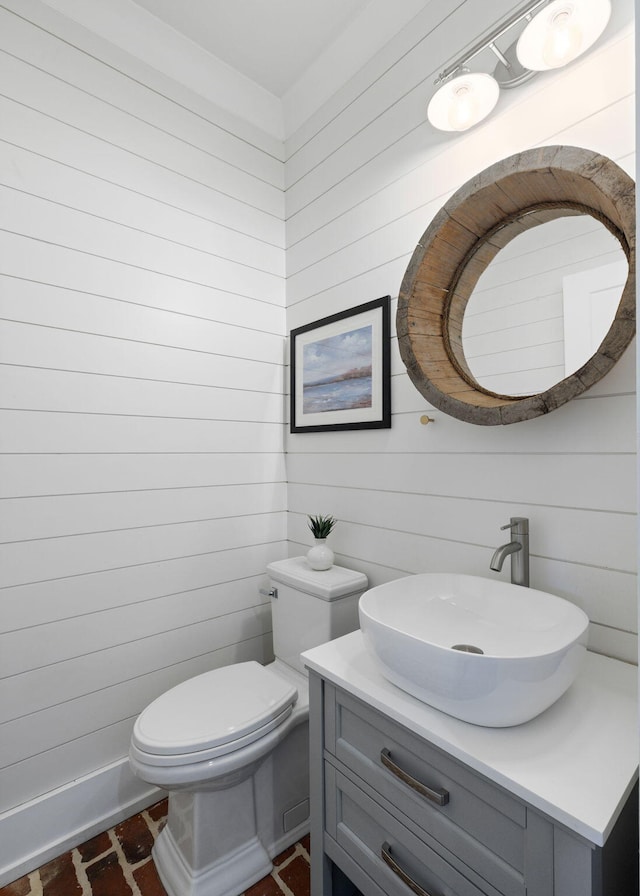 bathroom with wooden walls, vanity, and toilet