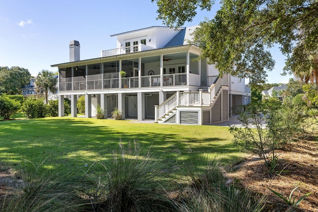 rear view of property featuring ceiling fan, a sunroom, and a lawn