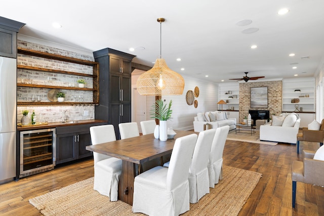 dining area with ceiling fan, beverage cooler, wet bar, and dark hardwood / wood-style flooring