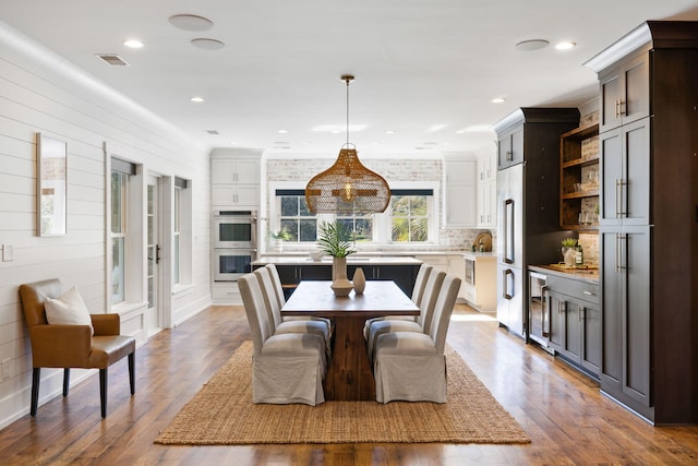 dining area with wooden walls, hardwood / wood-style floors, and wine cooler