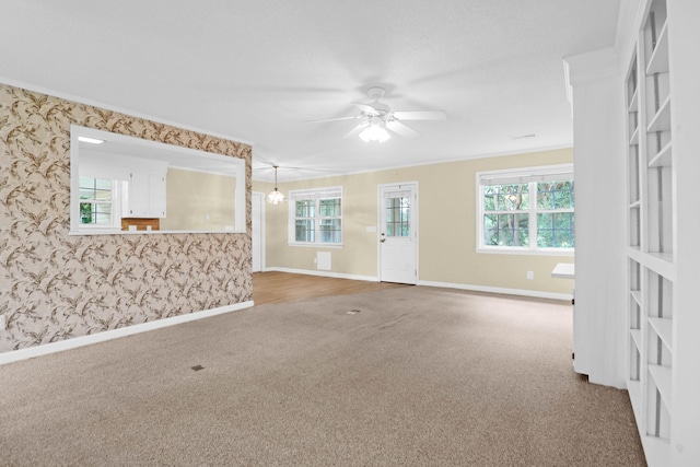 empty room with ceiling fan, plenty of natural light, crown molding, and carpet floors