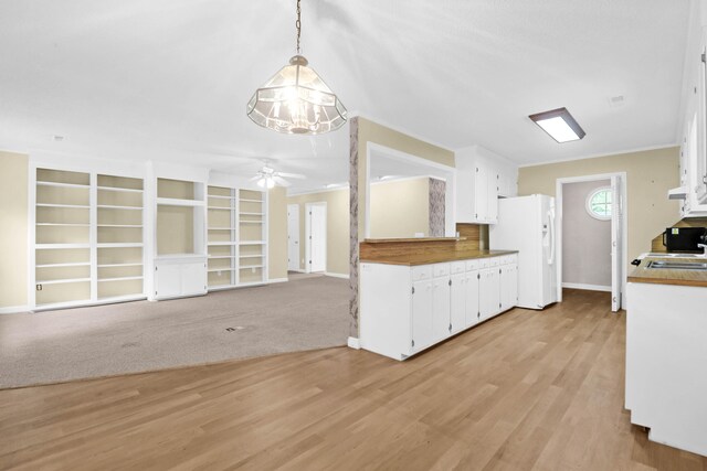 kitchen with pendant lighting, white refrigerator with ice dispenser, ceiling fan with notable chandelier, light hardwood / wood-style flooring, and white cabinets