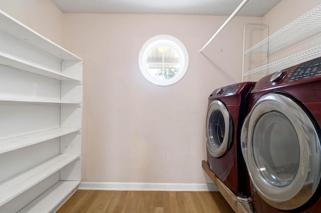 clothes washing area featuring light hardwood / wood-style flooring and washing machine and clothes dryer