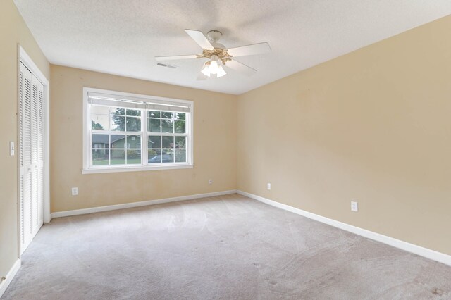 carpeted spare room with a textured ceiling and ceiling fan