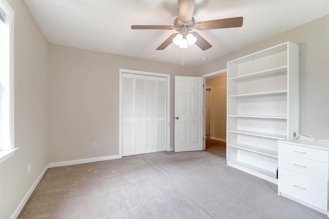 unfurnished bedroom featuring light colored carpet, ceiling fan, and a closet