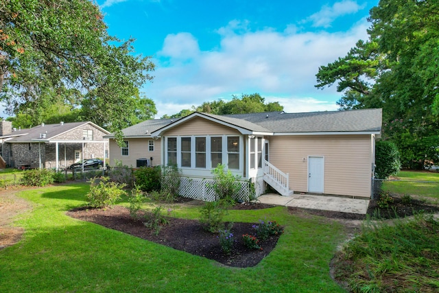 rear view of house with a yard and a sunroom