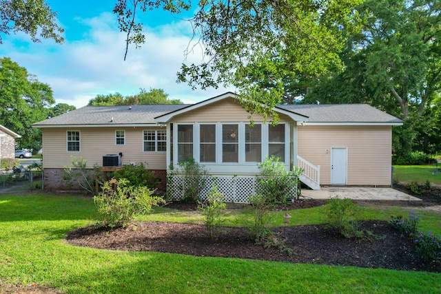 rear view of house featuring a sunroom, a yard, and central AC