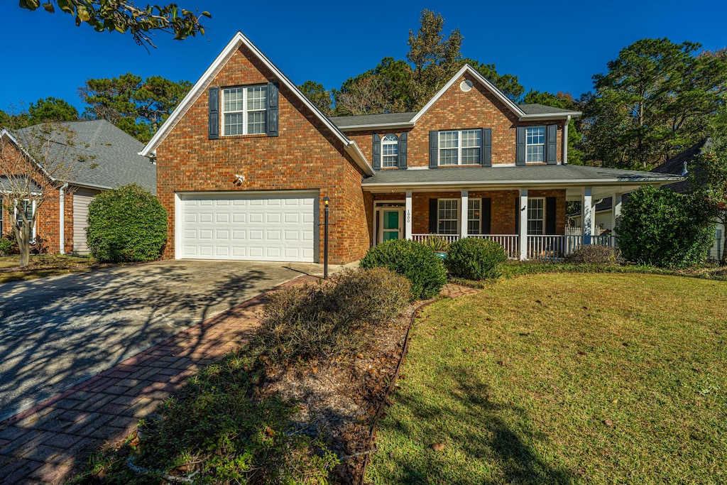 view of front of house with covered porch, a garage, and a front yard