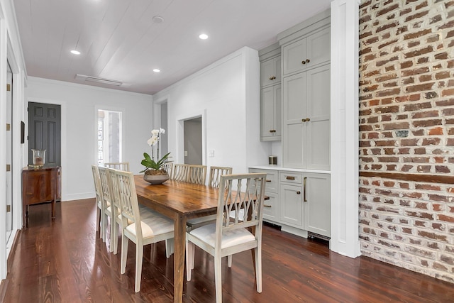 dining room with crown molding, brick wall, and dark hardwood / wood-style flooring