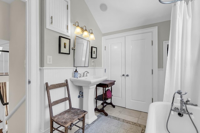 bathroom featuring sink, a tub, lofted ceiling, and tile patterned flooring