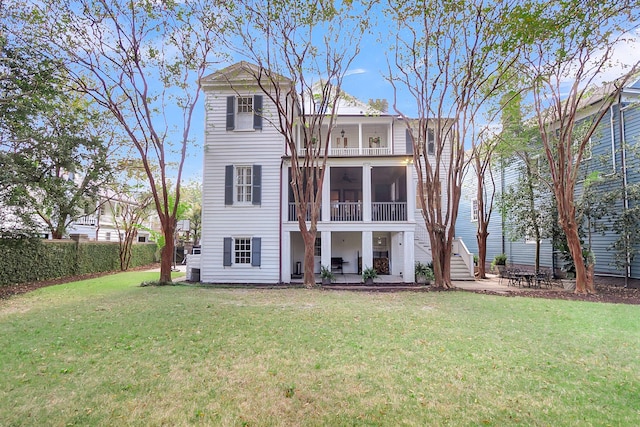 rear view of house featuring a patio, a lawn, and a sunroom