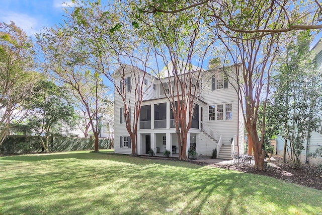 rear view of house featuring a yard and a sunroom