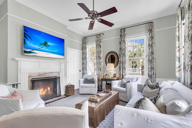 living room with crown molding, a premium fireplace, a wealth of natural light, and ceiling fan