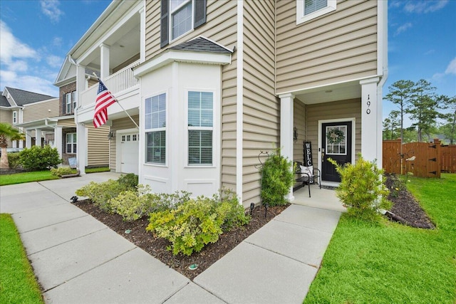 view of exterior entry with a garage and a balcony